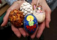 German pensioner Christa Kraft displays a selection of colourful hand-painted Easter eggs before decorating an apple tree with them, in the garden of her summerhouse in the eastern German town of Saalfeld, March 19, 2014. Each year since 1965 Volker and his wife Christa spend up to two weeks decorating the tree with their collection of 10,000 colourful hand-painted Easter eggs in time for Easter celebrations. REUTERS/Fabrizio Bensch