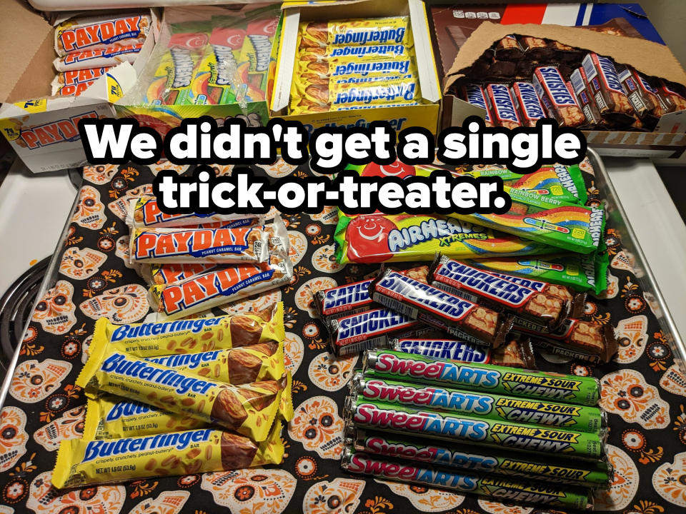 A pile of candy, and boxes of it in the background, with the caption "We didn't get a single trick-or-treater"