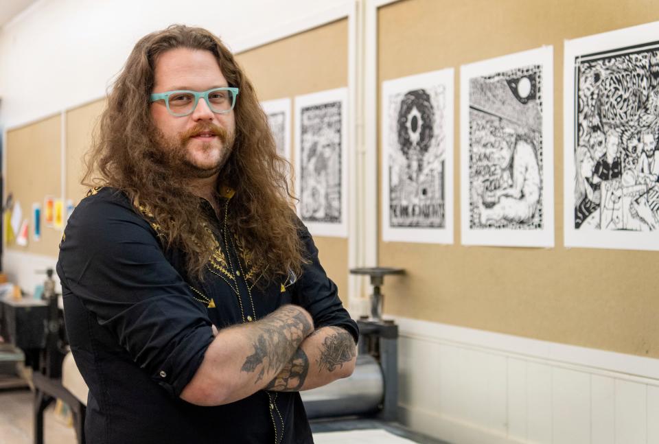 Local artist, author and educator Kyle Darnell poses in front of prints featured in his new book “Evansville Monsters II: The Book of Dark Days and Other Weird Tales” at the Univeristy of Evansville printmaking studio Tuesday, Nov. 21, 2023.