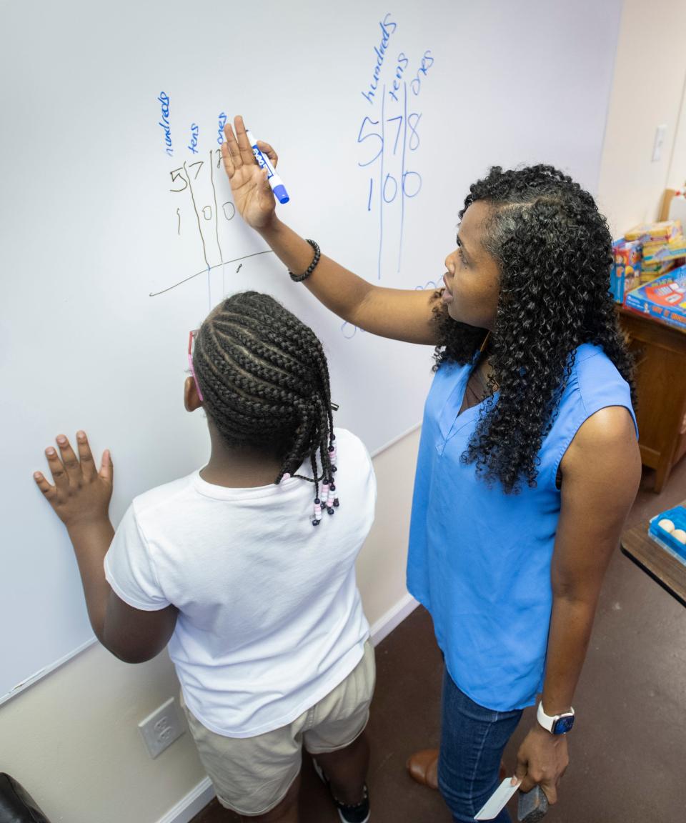 Kenita Mitchell helps a child with a math problem at Harmonic Learning Education and Training in Pensacola on Thursday. The center was awarded a $1,500 grant from Bantucola to help expand.
