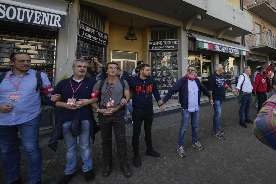 Demonstrators by the Italian Partisans association form a human chain to protect shops selling memorabilia of Fascist Dictator Benito Mussolini, during a march organized in Mussolini's birthplace Predappio Friday, Oct. 28, 2022, to mark the 78th anniversary of the liberation of the town from the nazi-fascist occupation by Italian Partisans and Polish allied troops, which coincides with the 100th anniversary of the march on Rome. (AP Photo/Luca Bruno)