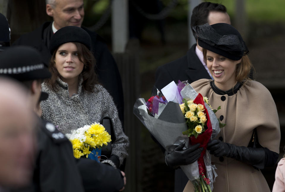 Britain's Queen Elizabeth II's granddaughters Princesses Beatrice, right, and Eugenie, left, hold flowers the Queen received from children after attending the British royal family's traditional Christmas Day church service in Sandringham, England, Tuesday, Dec. 25, 2012. (AP Photo/Matt Dunham)