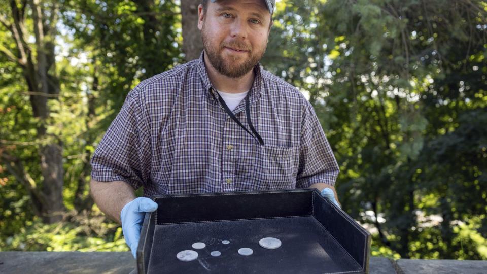 This photo, provided by the U.S. Military Academy at West Point, Aug. 30, 2023, shows West Point archeologist Paul Hudson displaying coins found in the lead box believed to have been placed in the base of a monument by cadets almost two centuries ago, in West Point, NY. (U.S. Military Academy at West Point via AP)