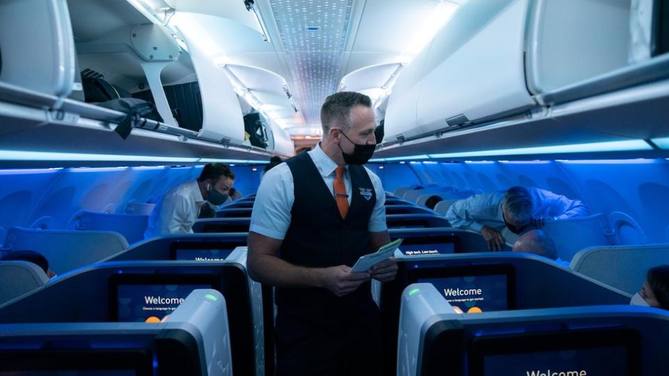 A flight attendant assists a passenger before a JetBlue flight to London at JFK International Airport in the Queens borough of New York City, New York, U.S., August 11, 2021.