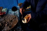 Wider Image: En un campo de inmigrantes en Francia, un hombre vende sándwiches para pagarle a los traficantes