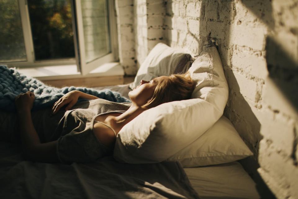 A woman dozes in bed by an open window