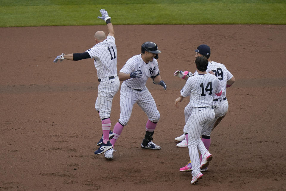 Teammates mob New York Yankees' Giancarlo Stanton, second from left, after he hit a walkoff single during the ninth inning of a baseball game against the Washington Nationals at Yankee Stadium, Sunday, May 9, 2021, in New York. (AP Photo/Seth Wenig)