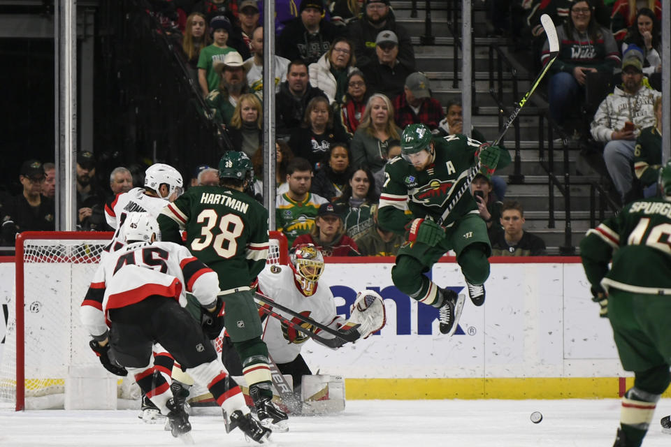 Minnesota Wild left wing Marcus Foligno, right, jumps out of the way of a shot that is blocked by Ottawa Senators goalie Anton Forsberg, second from right, as Wild right wing Ryan Hartman (38) looks on during the second period of an NHL hockey game Sunday, Dec. 18, 2022, in St. Paul, Minn. (AP Photo/Craig Lassig)