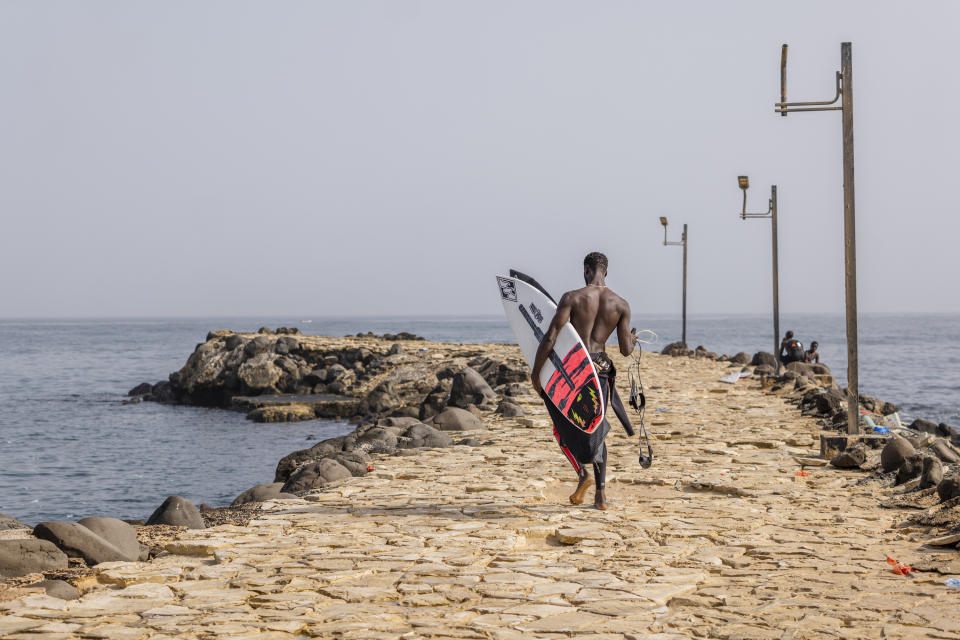 Cherif Fall, Senegal's number one surfer paddles to the wave in the Atlantic Ocean in Dakar, Senegal, Wednesday, Feb. 28, 2024. Instead of training in the waves off his Senegal homeland, Fall was wistfully preferring to be in Puerto Rico, where the last surfing qualifying competition for the Paris Olympics ends on Saturday. Senegal had nobody there to try and claim the last 14 spots for men and women because there was no money to send them, Fall says. (AP Photo/Sylvain Cherkaoui)