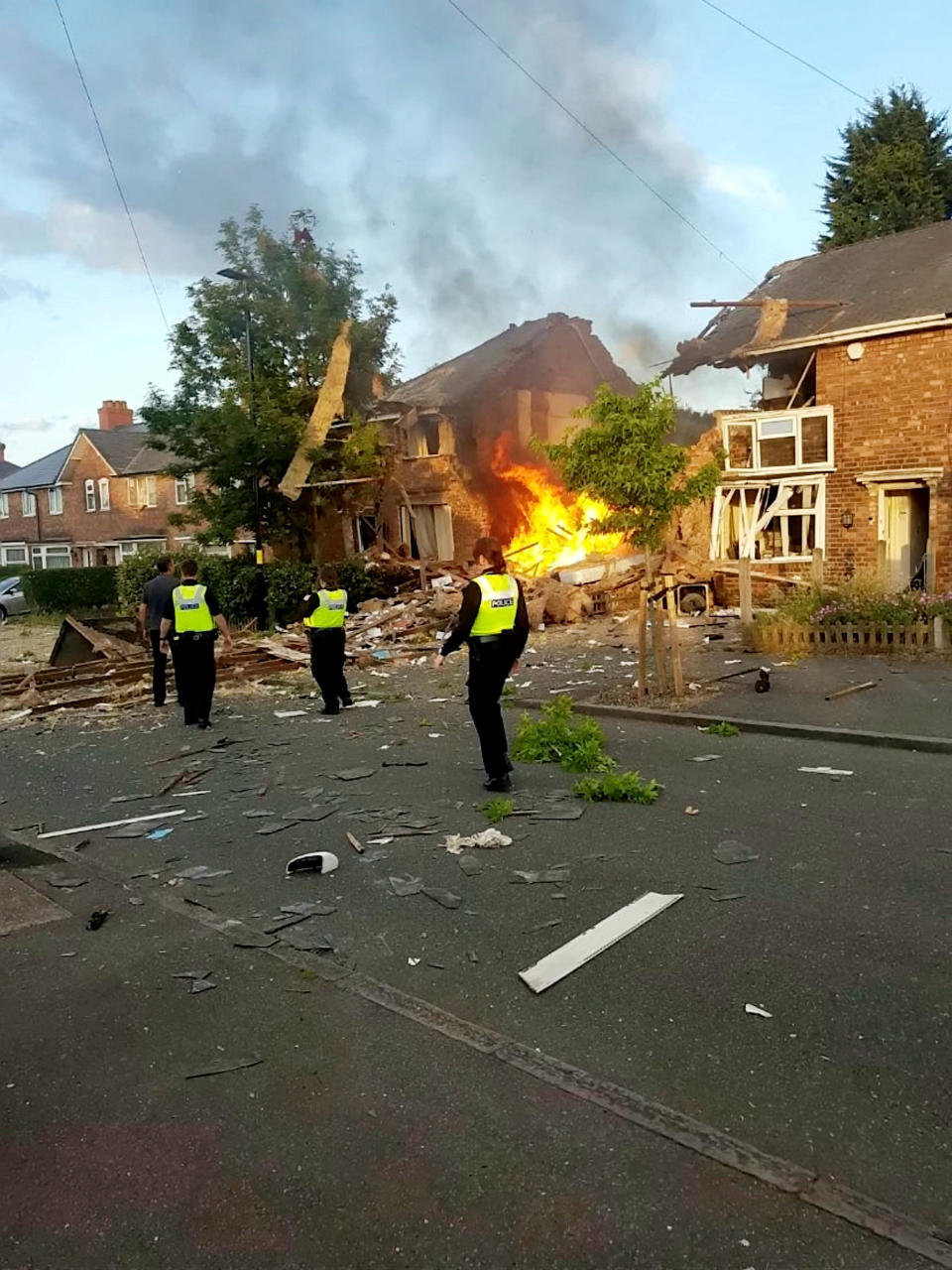 The scene of a dramatic house explosion on Dulwich Road in Kingstanding, Birmingham.  June 26, 2022.  See SWNS story SWMDblast.  Several people have been injured in a suspected gas blast which destroyed an entire house in Birmingham tonight (Sun).  Emergency services rushed to the scene in Dulwich Road, Kingstanding, at 8.38pm following reports of a “massive bang”.  Shocking pictures show flames engulfing the semi-detached property and bricks and debris strewn across the residential street. One house is destroyed with others significantly damaged. Cars have also been wrecked.  There are reports of casualties but the number and severity of their injuries in unknown at this time.  West Midlands Police said all emergency services and utility companies are that the scene of the blast while residents in nearby properties were evacuated. 