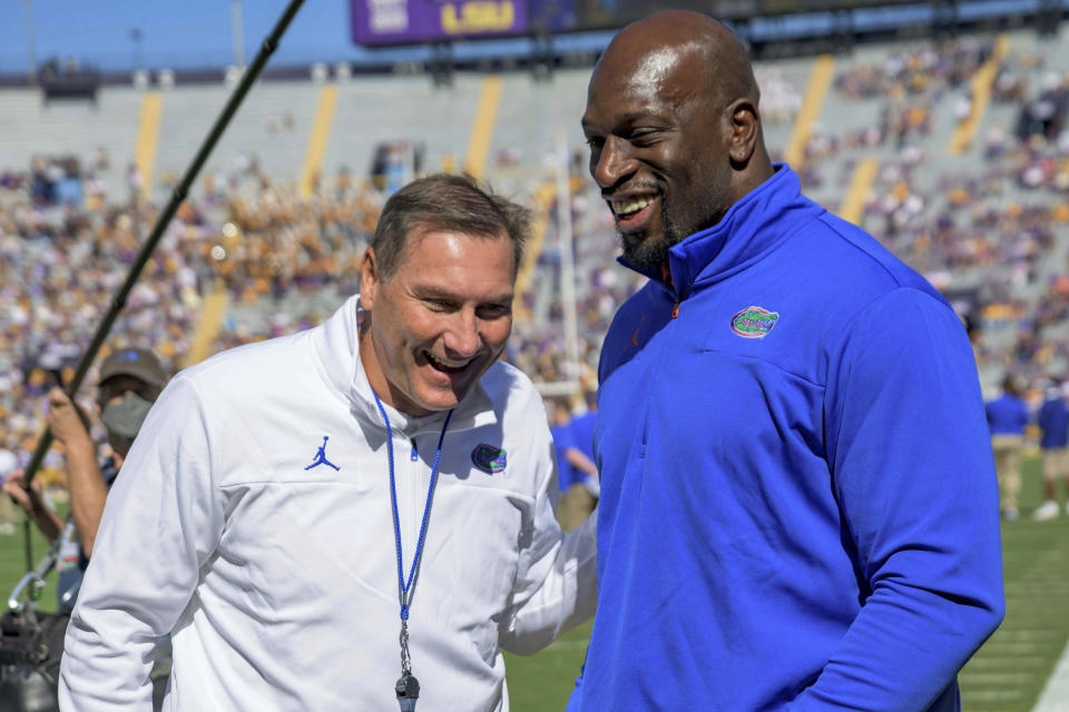 Florida head coach Dan Mullen talks with WWE Superstar Titus O'Neil, who previously played for the University of Florida with his given name of Thaddeus Bullard, Sr., before an NCAA college football game against LSU in Baton Rouge, La., Saturday, Oct. 16, 2021. (AP Photo/Matthew Hinton)