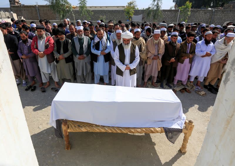 FILE PHOTO: Afghan men pray in front of the coffin of one of three female media workers who were shot and killed by unknown gunmen, in Jalalabad