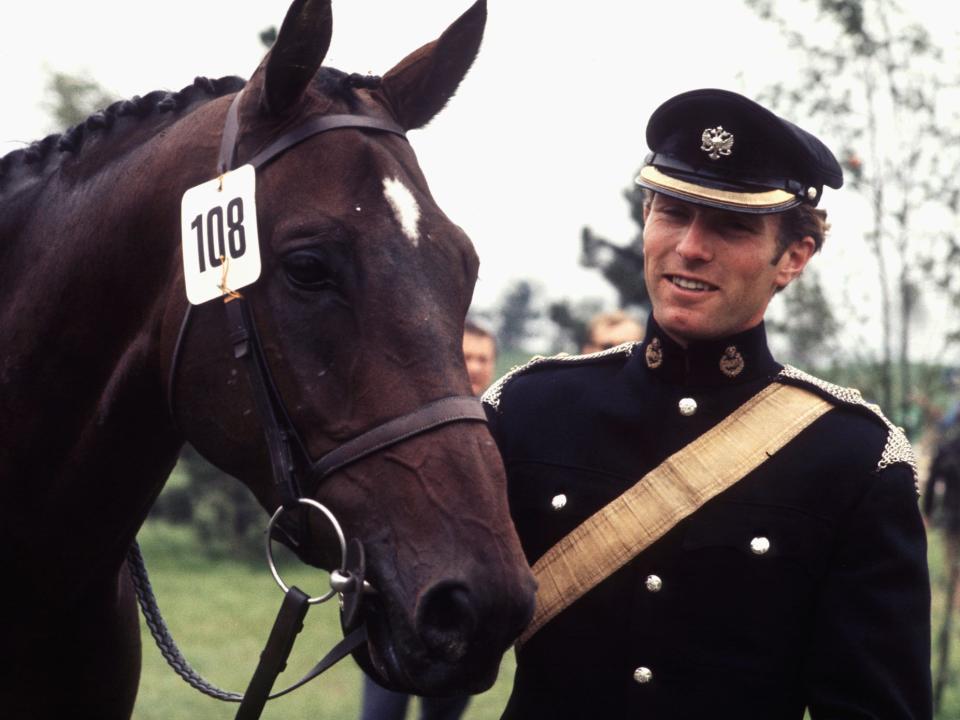 Mark Phillips stands next to a horse.