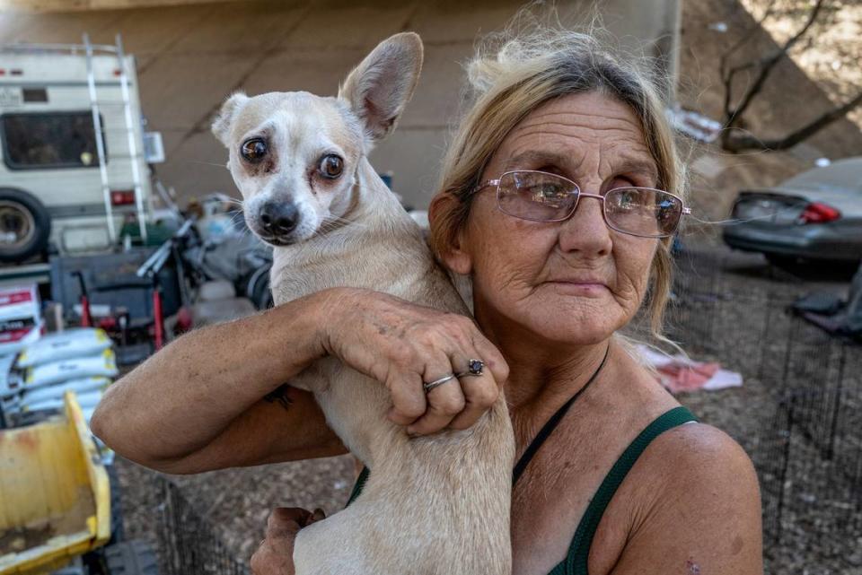 Gwen Mayse, 62, holds her daughter’s dog Princess at an homeless encampment underneath a freeway overpass where she lives in a tent in north Sacramento on Thursday, Aug. 25, 2022.