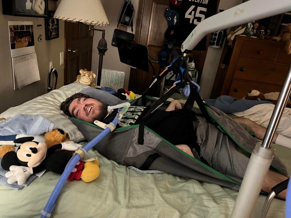 Michael lays in bed, wrapped in his lift, which brings him comfortably to his specialized wheelchair.