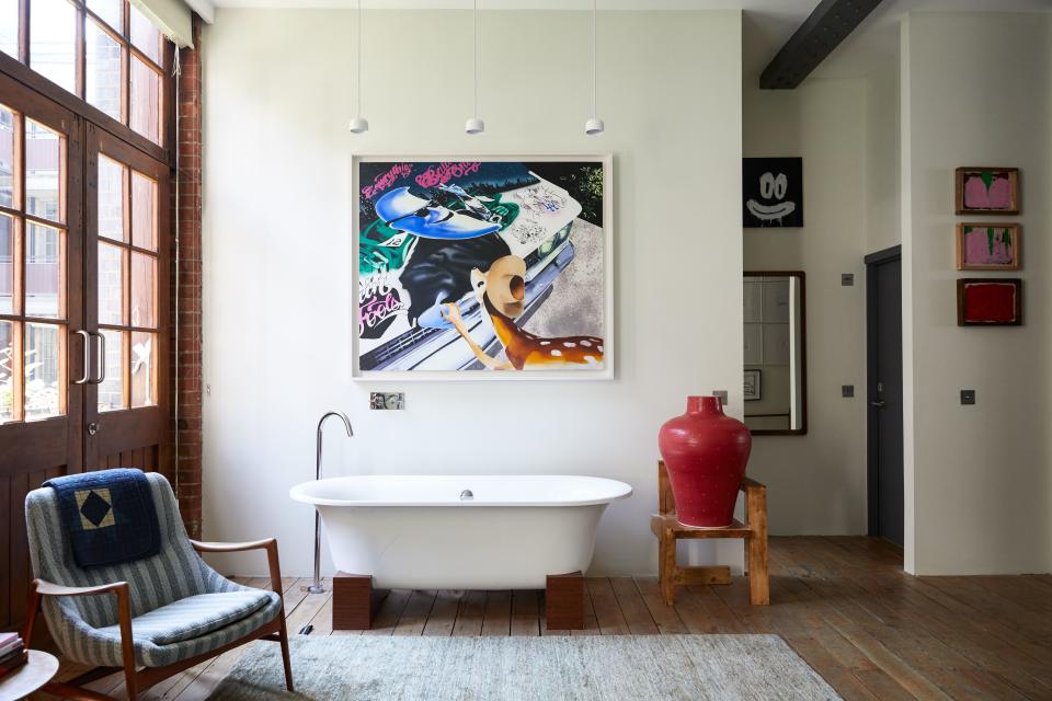 In Tovey’s bedroom, an elegant bath sits under a painting by Jamie Juliano Villani, next to a design-classic chair by Gerrit Rietveld that supports a strawberry-inspired vase by Los Angeles–based artist Shio Kusaka. The rug, like many in the apartment, is by Spanish designer Nani Marquina: “I love the solid quality of her designs.” Above the bath hangs a trio of lights by British lighting designer Terence Woodgate. In the background, a work by Joyce Pensato and three pieces by Alvaro Barrington.