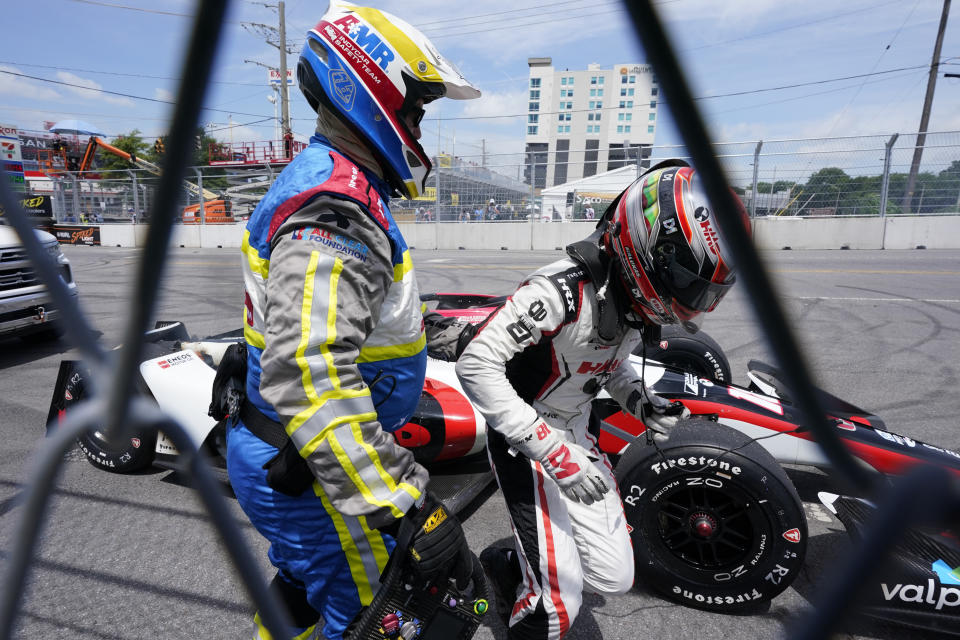 David Malukas, right, is helped out his car after it caught fire near Turn 9 during the Music City Grand Prix auto race Sunday, Aug. 6, 2023, in Nashville, Tenn. (AP Photo/George Walker IV)