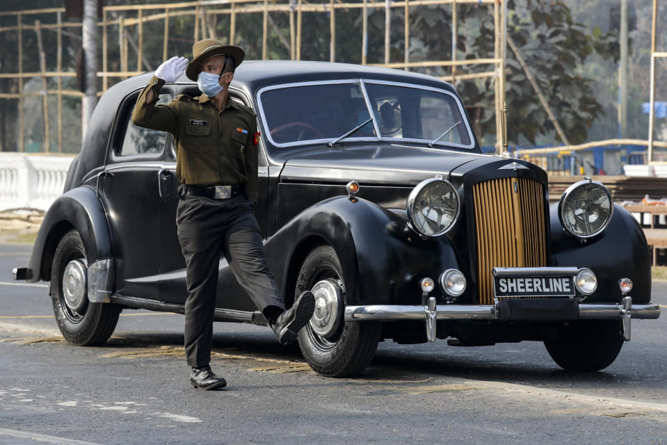 An Indian army soldier wearing a face mask to prevent the spread of the coronavirus marches alongside a vintage 1940 Austin A125 Sheerline car during rehearsals for Republic Day parade in Kolkata, India, Friday, Jan. 22, 2021. (AP Photo/Bikas Das)