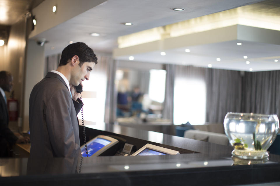 Man behind a hotel reception desk on the phone