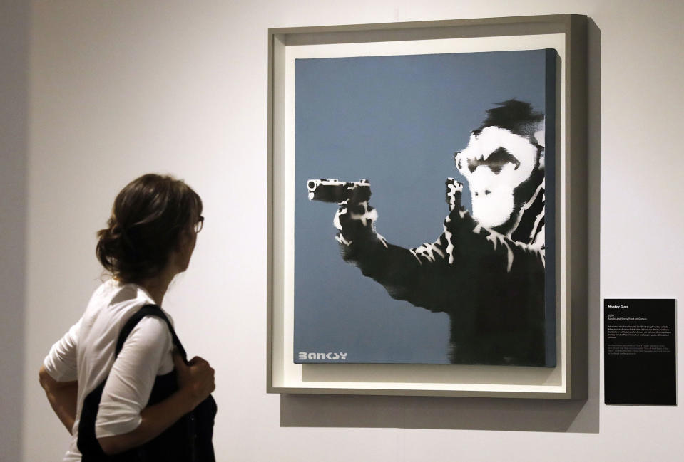 <p>A visitor looks at the painting ‘Monkey Guns’ by British Banksy during the exhibition ‘The Art of Banksy’ in Berlin, Germany on June 20, 2017. (Felipe Trueba/EPA/REX/Shutterstock) </p>