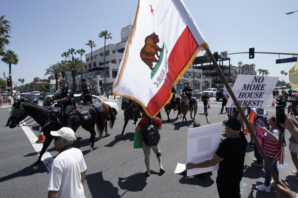 Law enforcement personnel on horseback keep protestors on the sidewalk during a May Day demonstration at the pier Friday, May 1, 2020, in Huntington Beach, Calif. (AP Photo/Chris Carlson)