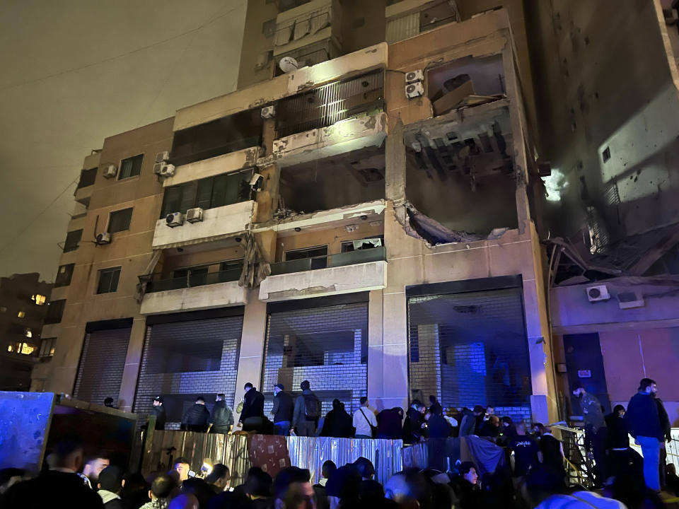 Varias personas afuera de un edificio tras una explosión en el sur de Beirut, Líbano, el martes 2 de enero de 2024. (AP Foto/Hussein Malla)