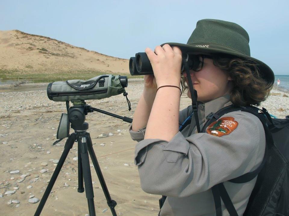 In this May 30, 2019 photo, Erica Adams, wildlife technician and lead piping plover staffer at Sleeping Bear Dunes, looks for the nesting birds in Glen Haven, Mich. Trouble is brewing for the piping plovers, already one of the Great Lakes region's most endangered species, as water levels surge during a rain-soaked spring that has flooded large areas of the Midwest. (AP Photo/John Flesher)