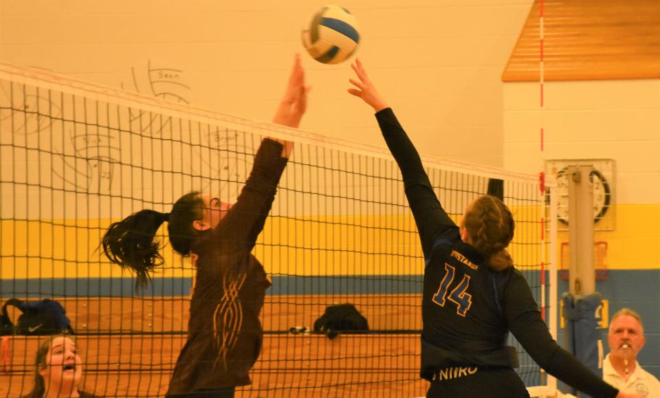 Mt. Markham Mustang Paige Korosec (14) tips the ball over the net and a Canastota block during Tuesday's Section III semifinal match.