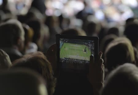 A spectator takes a photograph on an iPad during the men's singles final tennis match between Novak Djokovic of Serbia and Roger Federer of Switzerland at the Wimbledon Tennis Championships, in London July 6, 2014. REUTERS/Toby Melville