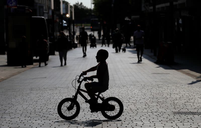 A child cycles his bike across a quiet shopping street following the outbreak of the coronavirus disease (COVID-19) in St Helens