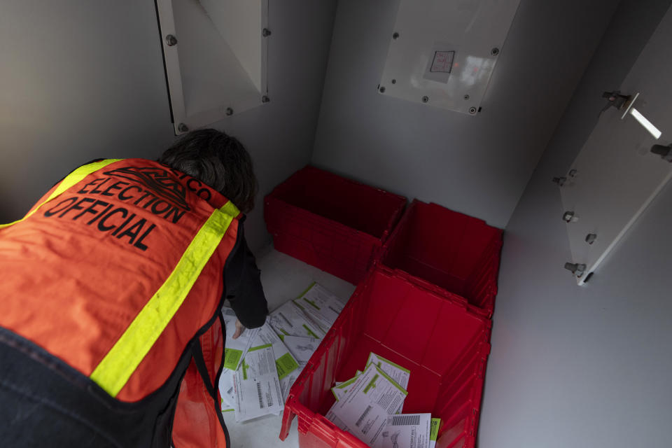 An election official gathers vote-by-mail ballots from inside a dropbox outside the Multnomah County elections office on Tuesday, May 21, 2024, in Portland, Ore. (AP Photo/Jenny Kane)