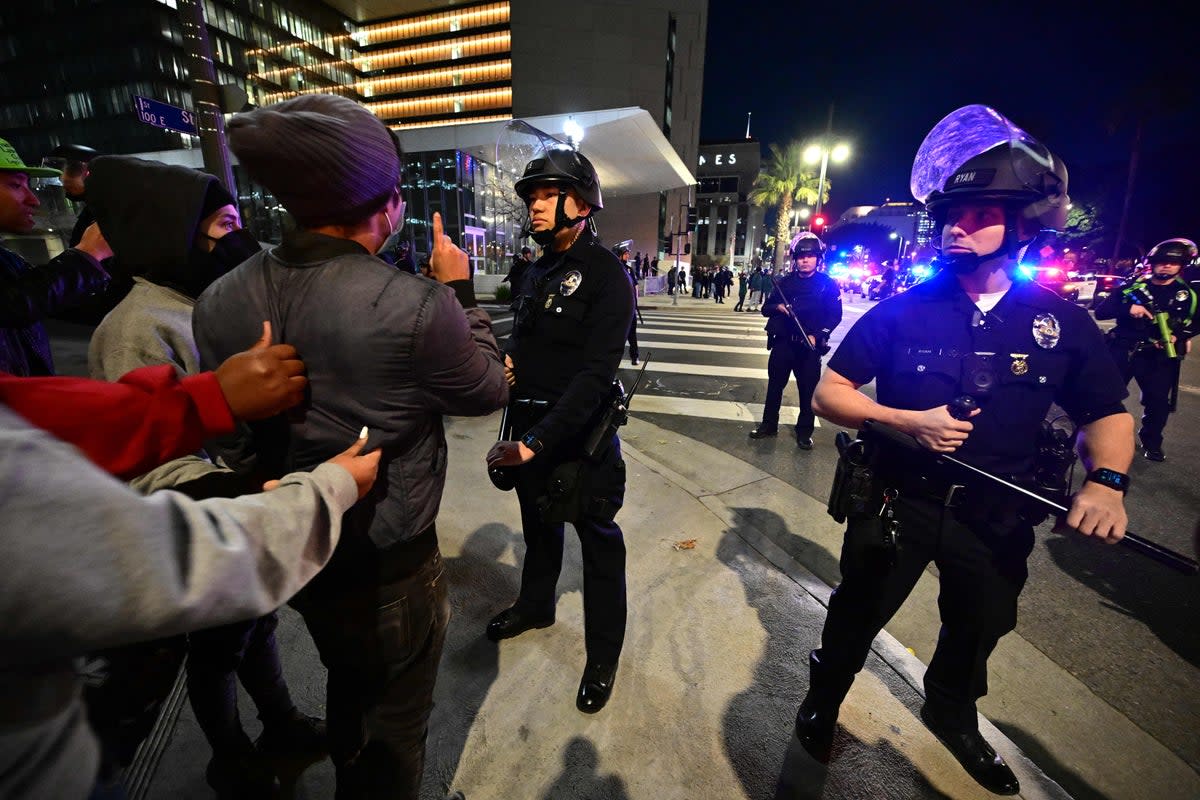 Protesters face off with police officers during a rally outside the LAPD headquarters, in Los Angeles (AFP)