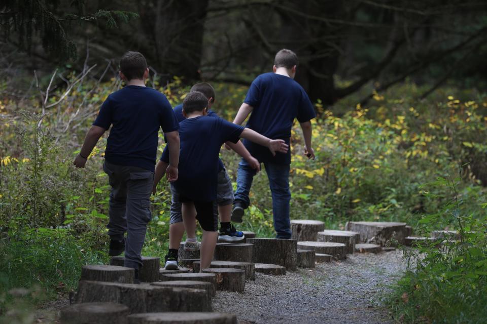 Students at Perry Elementary School walk along stumps in the Playful Path of the Autism Nature Trail on October 15, 2021.  The Autism Nature Trail is located next to the Humphrey Nature Center at Letchworth State Park.