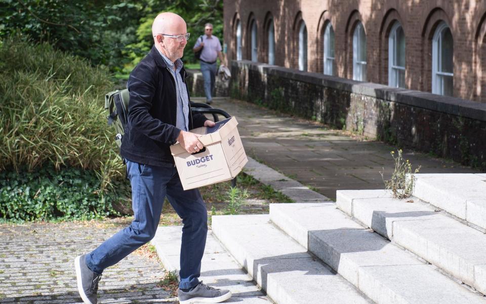 Sean O'Neill carries a file box up the steps leading to Devon County Hall