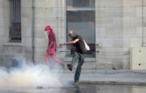 A demonstrator kicks a gas canister at a protest during the G7 summit, in Bayonne