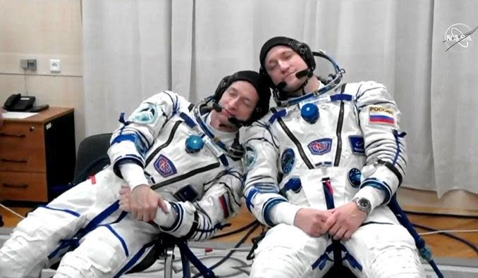 Calm cosmonauts? Commander Sergey Ryzhikov, left, and flight engineer Sergey Kud-Sverchkov take a quick nap -- or pretend to -- during suit-up before launch.  / Credit: NASA/Roscosmos