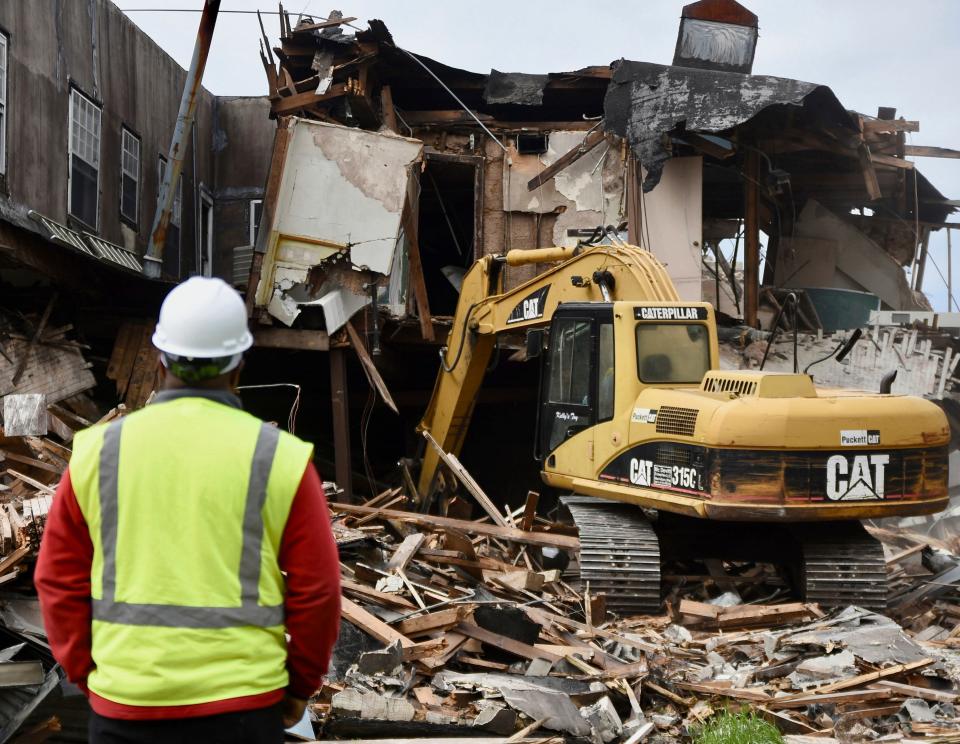 A worker watches as a backhoe operator uses the heavy machinery to pull down large pieces of the E.F. Young Jr. Hotel in Meridian, Miss., on Monday, April 24, 2023. First opened in 1946, the hotel was for years one of the only places in Meridian that provided lodging for traveling African Americans, and was listed on the National Register of Historic Places.