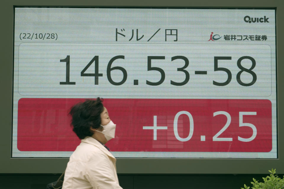 A person wearing a protective mask rides a bicycle in front of an electronic stock board showing Japanese yen/U.S. dollar conversion rate at a securities firm Friday, Oct. 28, 2022, in Tokyo. Inflation has been rising in Japan along with globally surging prices. A weakening of the yen against the dollar has amplified costs for imports. (AP Photo/Eugene Hoshiko)
