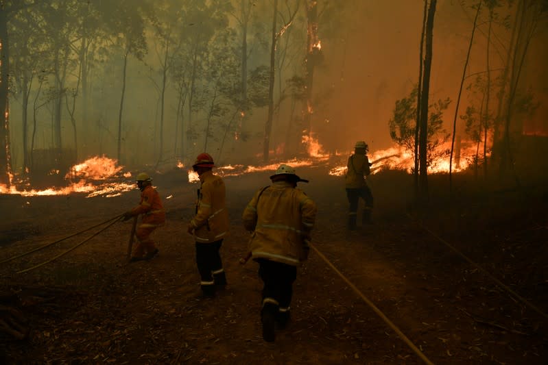 RFS volunteers and NSW Fire and Rescue officers protect a home on Wheelbarrow Ridge Road being impacted by the Gospers Mountain fire near Colo Heights south west of Sydney