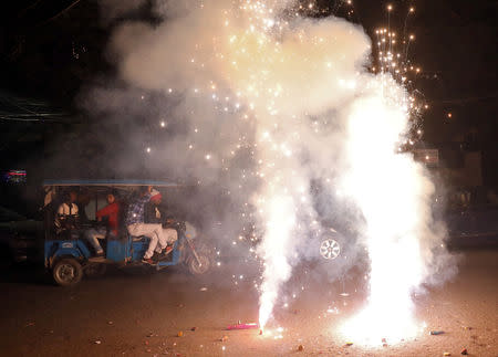 Men travel in a trishaw as firecrackers burn on a street during Diwali, the Hindu festival of lights, in New Delhi, India, November 7, 2018. REUTERS/Anushree Fadnavis