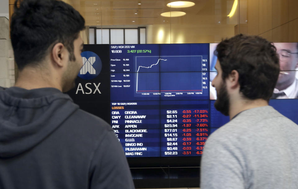 Men watch the public display boards at the Australian Stock Exchange in Sydney, Thursday, Aug. 15, 2019. Asian stock markets followed Wall Street lower on Thursday after the Dow Jones Industrial Average plunged on mounting fears of a possible recession. (AP Photo/Rick Rycroft)