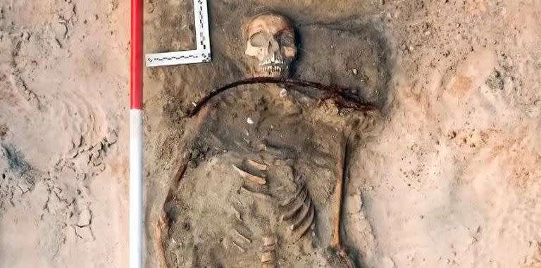 Investigadores en Polonia excavaron a una mujer del siglo XVII enterrada con una hoz alrededor del cuello y un candado en el pie. Cerca estaban los restos de un niño con un candado bajo el pie (Łukasz Czyżewski)