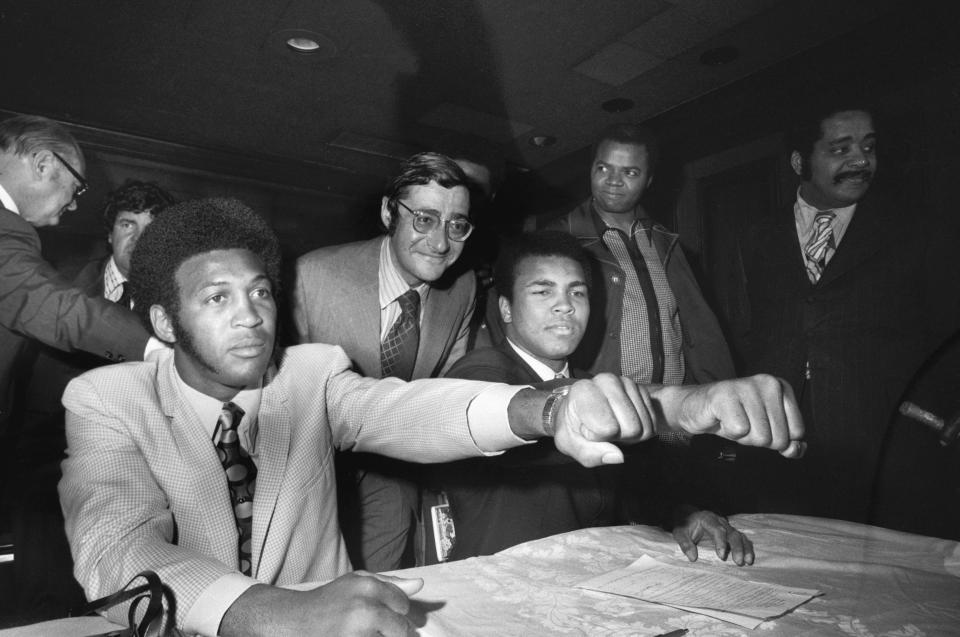 (Original Caption) Muhammad Ali (R), the 29-year-old former heavyweight champion of the world, compares fists with Jimmy Ellis, the 31-year-old former WBA champion, at their meeting with the press 6/2 where they signed to fight a 12-round bout in the Astrodome in Houston, Texas 7/26. Standing between the two contenders is Bob Arum, president of Top Rank, Inc., promoters of the bout.