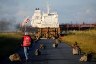 A French CGT labour union employee walks near a barricade to block the entrance of the fuel depot of the society SFDM near the oil refinery of Donges, France, May 23, 2016. REUTERS/Stephane Mahe