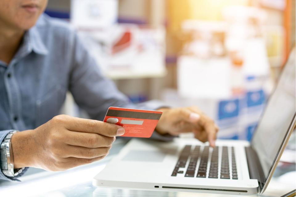 Man holding credit card and typing on laptop computer