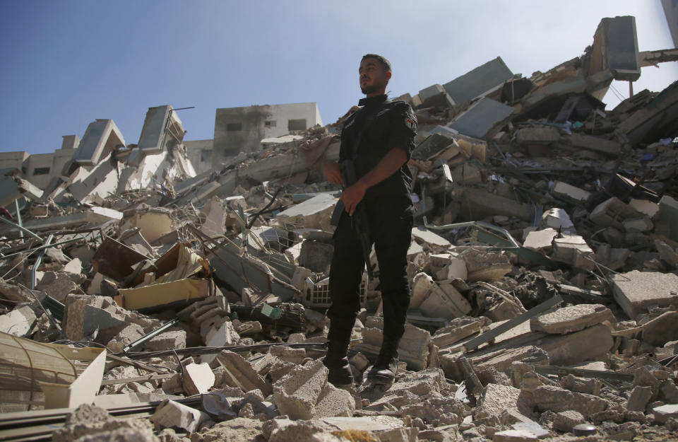 A policeman stands on rubble from a building housing AP office and other media in Gaza City that was destroyed after Israeli warplanes demolished it, Saturday, May 15, 2021. The airstrike Saturday came roughly an hour after the Israeli military ordered people to evacuate the building. There was no immediate explanation for why the building was targeted. (AP Photo/Hatem Moussa)