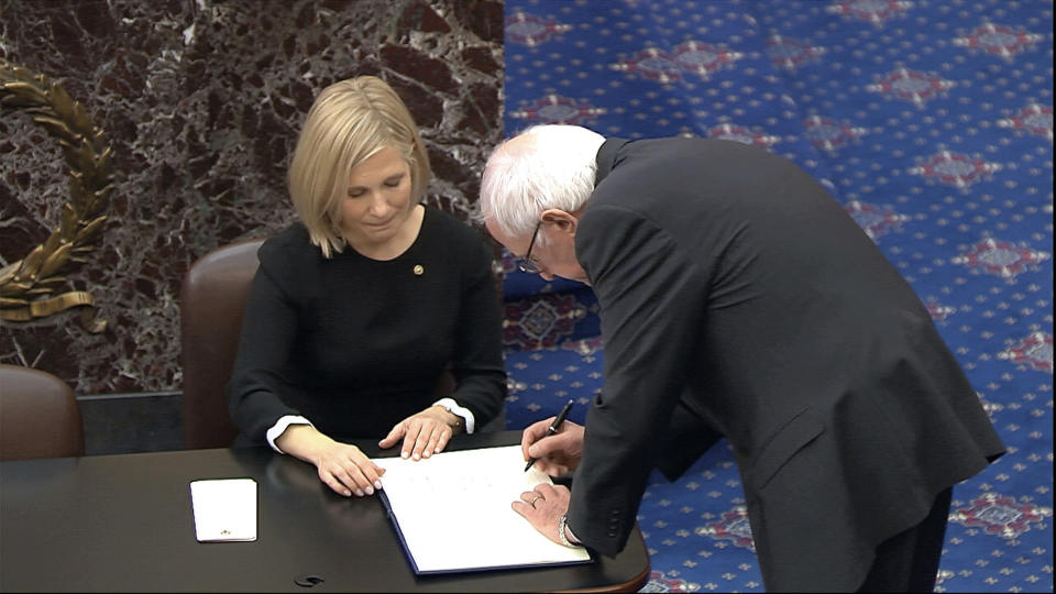 In this image from video, Sen. Bernie Sanders, I-Vt., signs the oath book after being sworn in for the impeachment trial of President Donald Trump in the Senate at the U.S. Capitol in Washington, Thursday, Jan. 16, 2020. (Senate Television via AP)