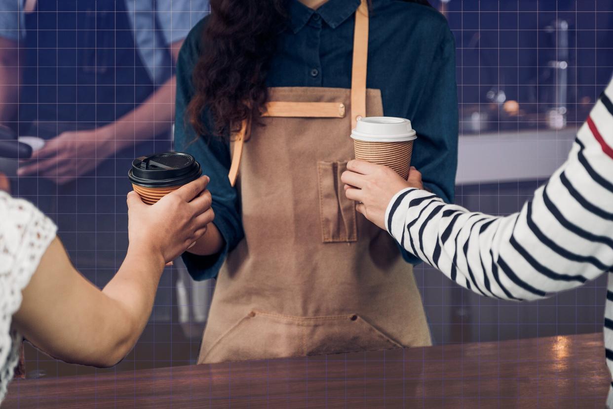 a barista handing coffees to customers