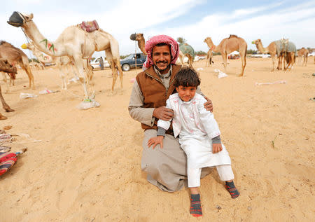 Salman Awied, 35, sits with his son Hamza, a 5-year-old trainee jockey, during the opening of the 18th International Camel Racing festival at the Sarabium desert in Ismailia, Egypt, March 12, 2019. Picture taken March 12, 2019. REUTERS/Amr Abdallah Dalsh