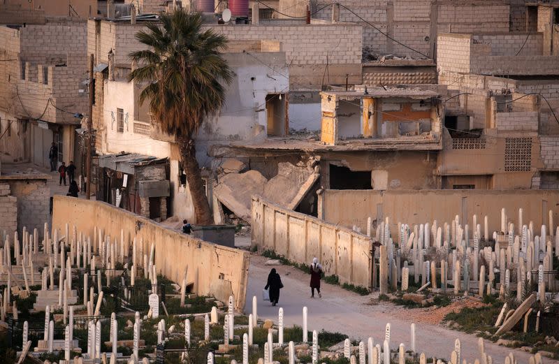 People walk near a cemetery in Douma